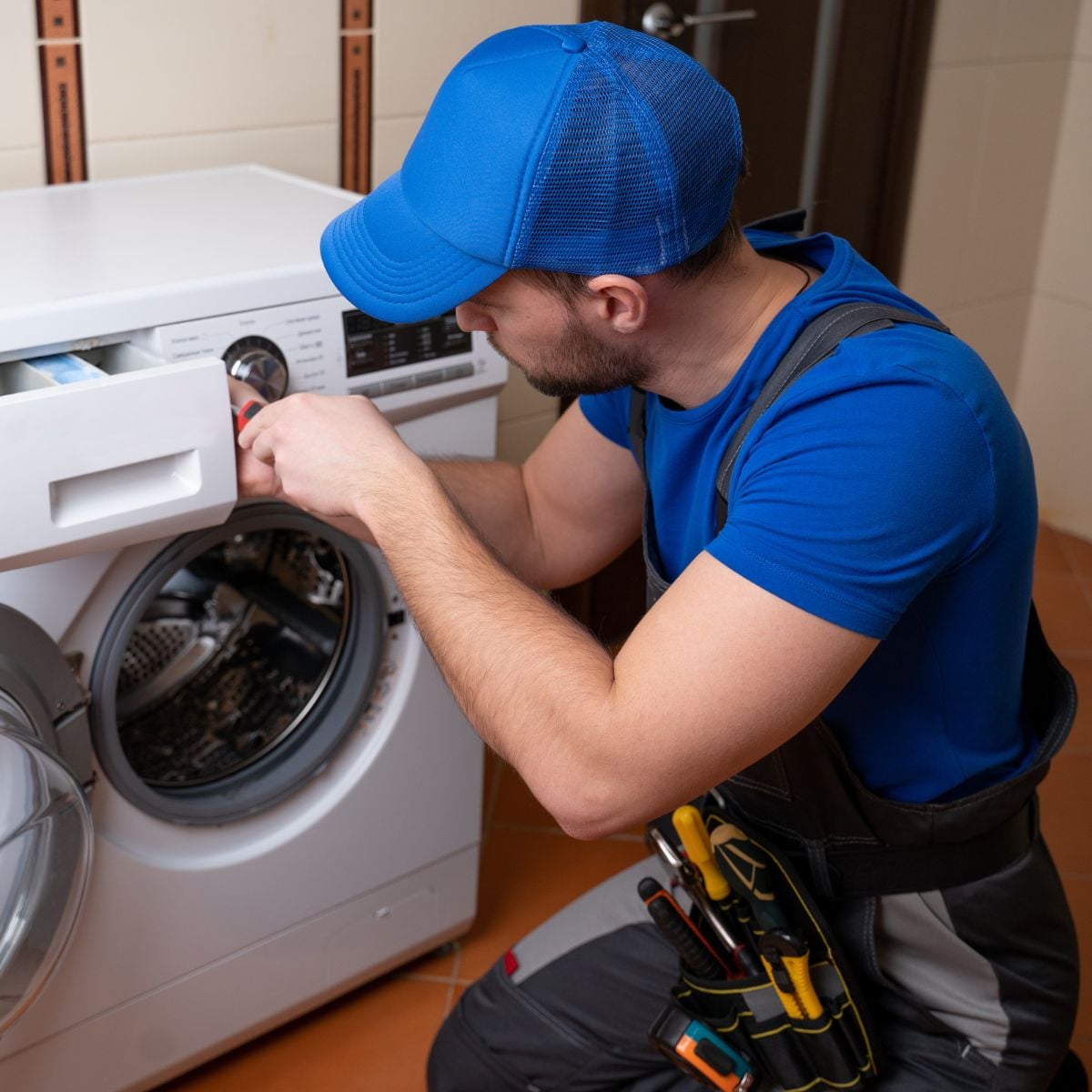 Technician using a screwdriver to service the detergent drawer of a front-load washing machine