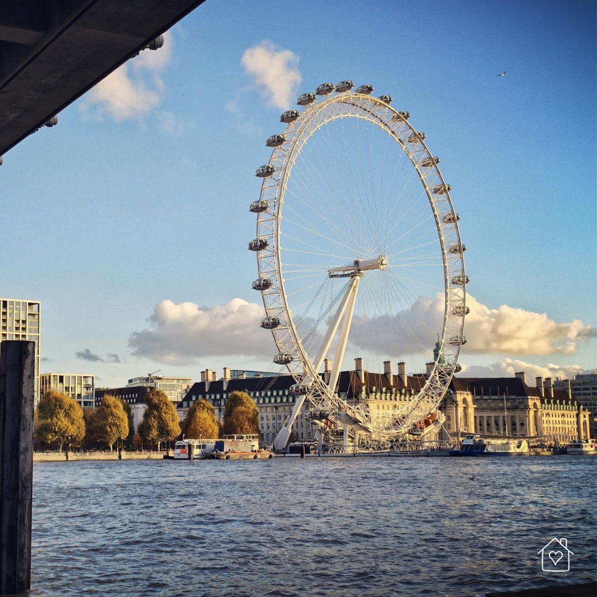 View of the London Eye overlooking the River Thames on a calm, sunny afternoon in London.
