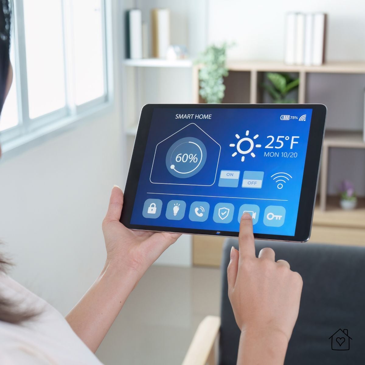 Person holding a tablet with a smart home control dashboard showing temperature, Wi-Fi connection, and connected devices in a modern living room.