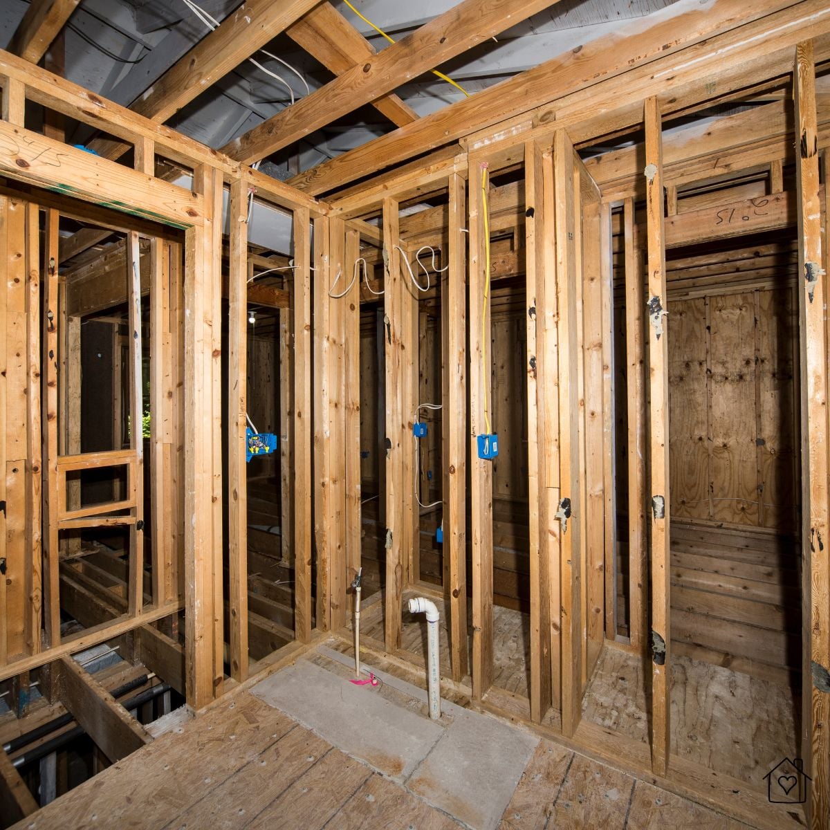 Framed interior wall showing electrical boxes and plumbing rough-in during a full gut home renovation.