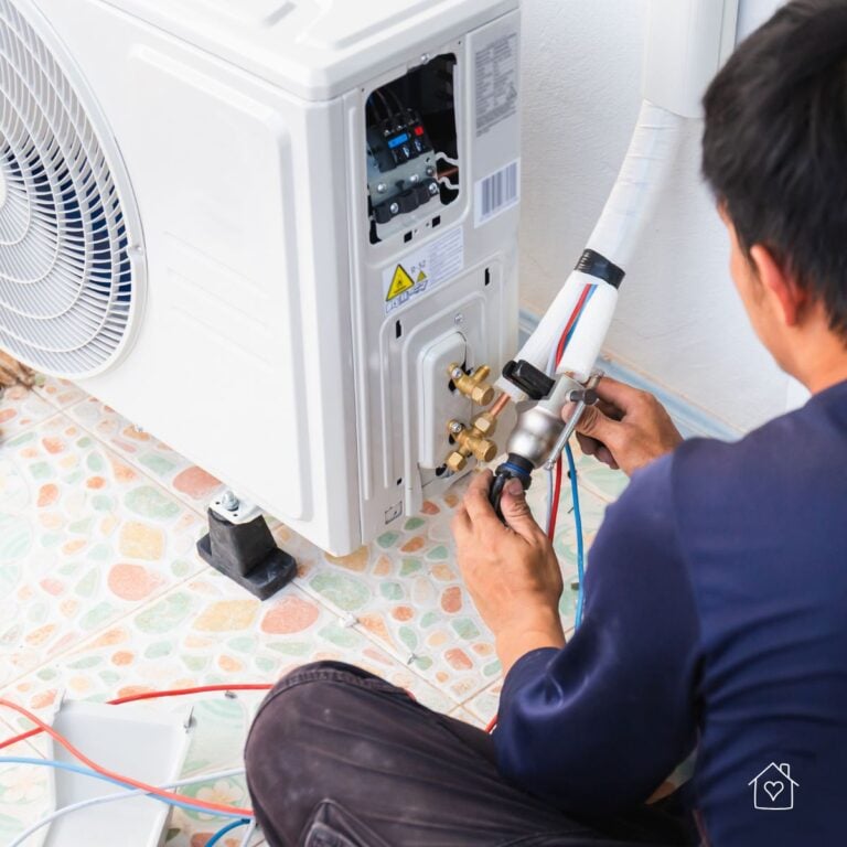 Technician connecting gauges and lines to an outdoor condenser unit during service