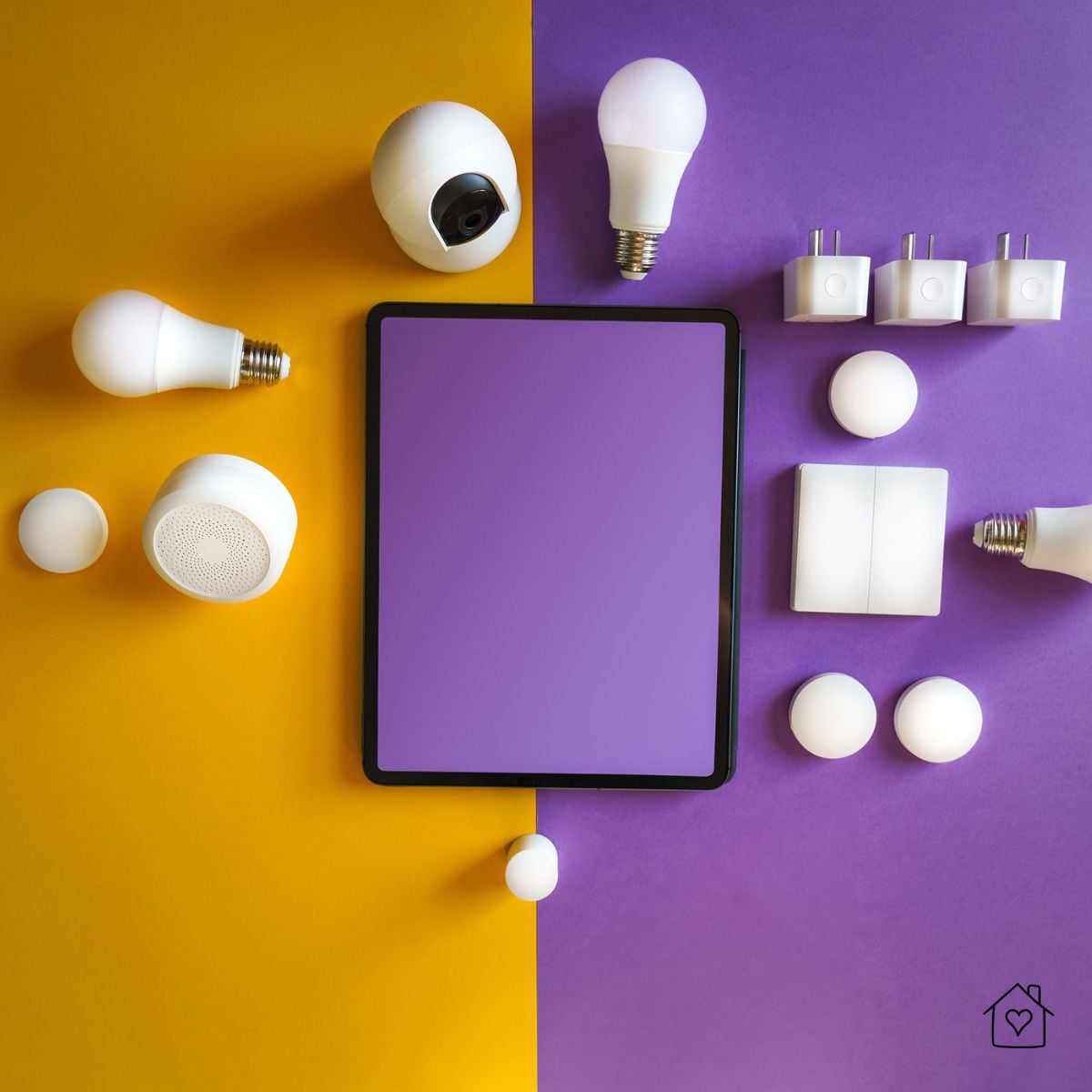 Flat lay of a tablet surrounded by smart light bulbs, plugs, sensors, and hubs on a yellow and purple background, representing a home filled with connected devices.