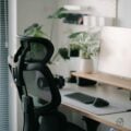 Modern home office with ergonomic mesh chair, adjustable headrest, and eye-level monitor.