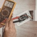 Electrician testing wiring with a multimeter during a full gut home renovation.