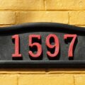 Close up of elegant house numbers on a yellow brick wall