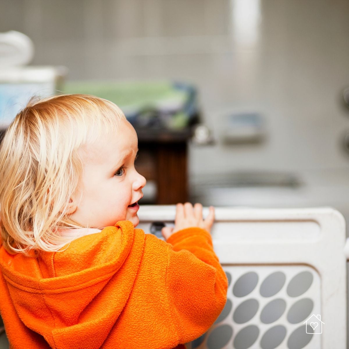 Toddler standing behind a safety gate in a childproofed home.