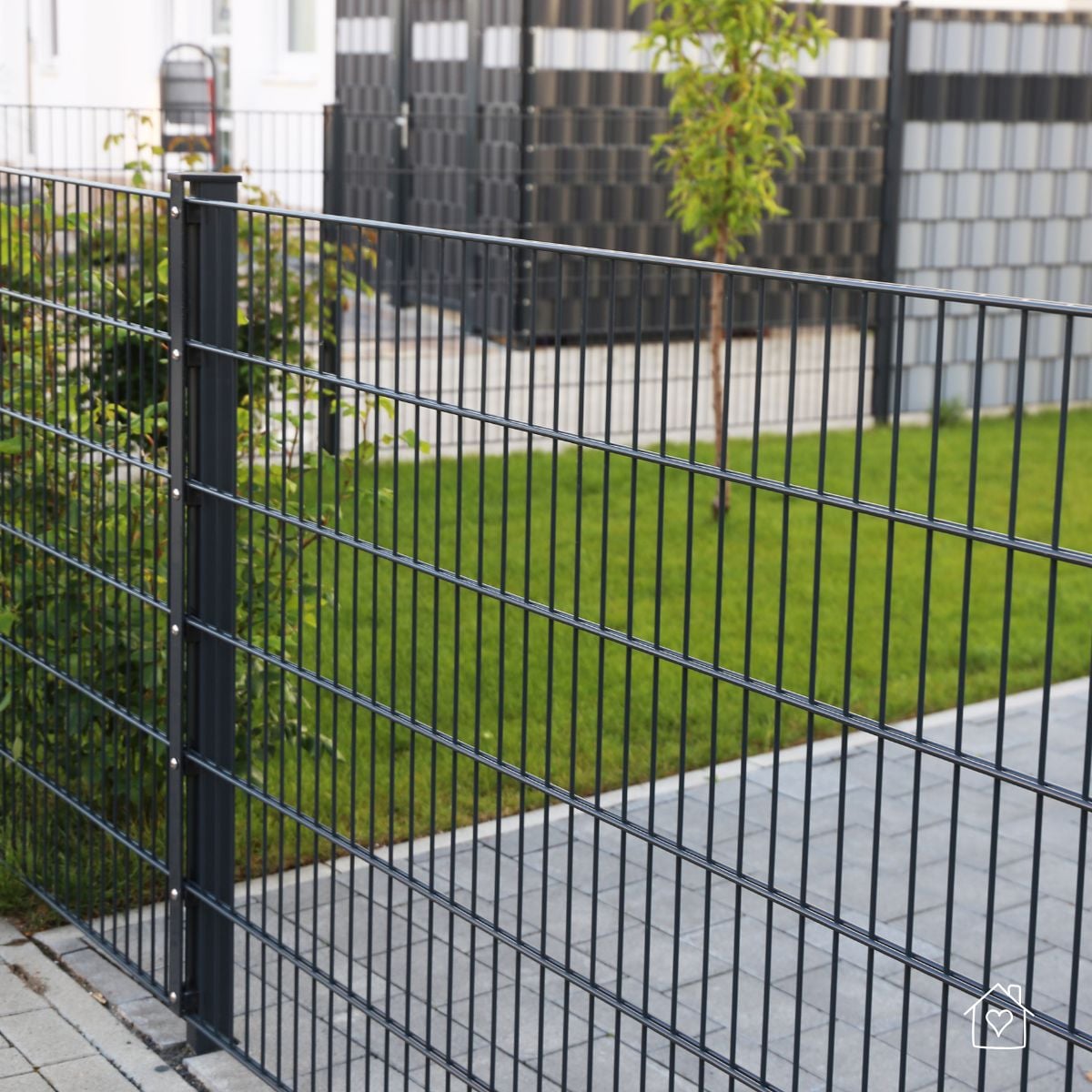 Black metal wire garden fence installed around a landscaped backyard lawn