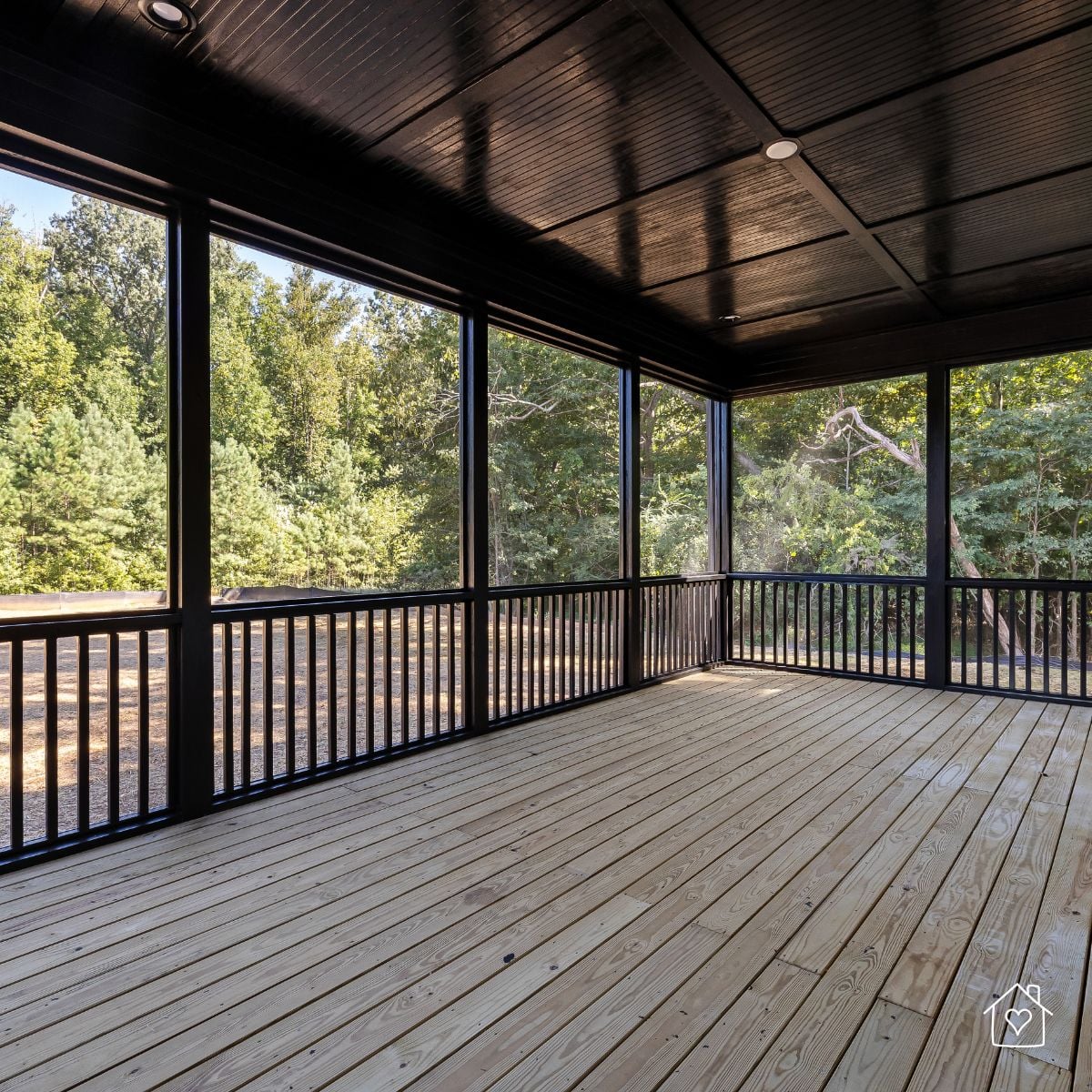 screened porch with wood floor, black ceiling, and forest view