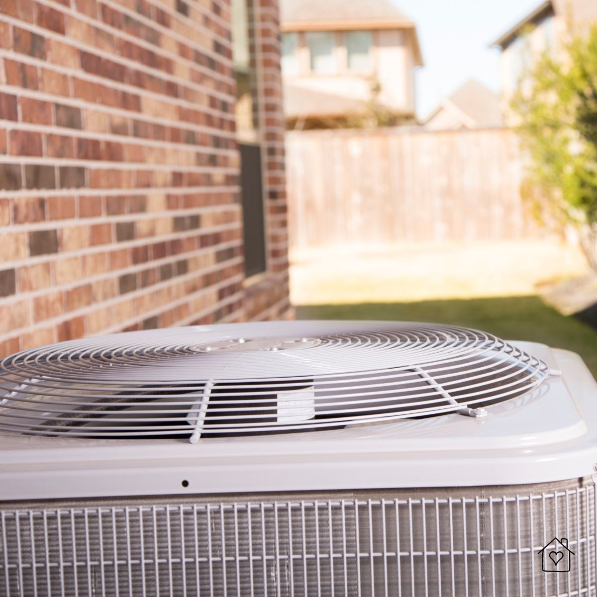 Top view of a residential air conditioner condenser unit installed beside a brick home in Alabama