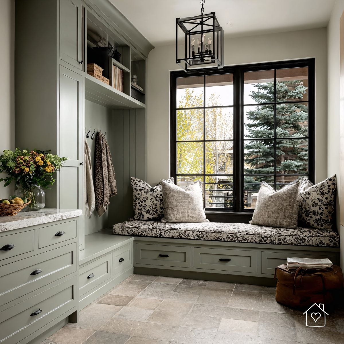 Mudroom with sage built-ins, cushioned bench, black-frame windows, and lantern pendant.