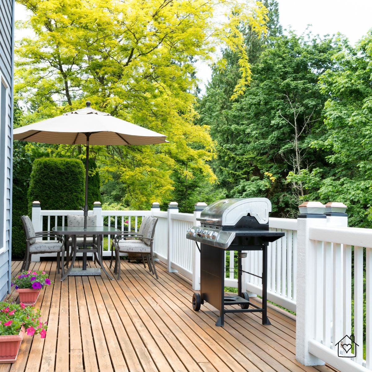 backyard deck with grill, patio table, umbrella, and white railing