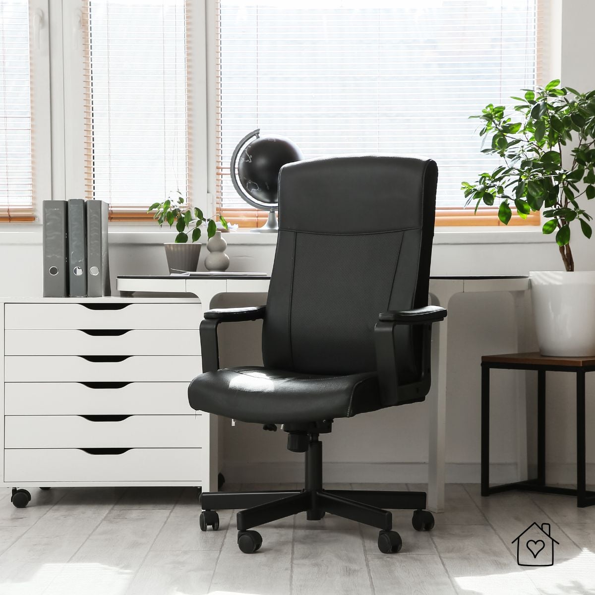 Black high-back office chair in a bright home office&mdash;an example of a high quality refurbished office chair with supportive padding and stable base.