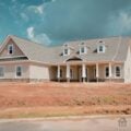 Newly built home exterior showing brick facade, gray roof, and front porch columns.