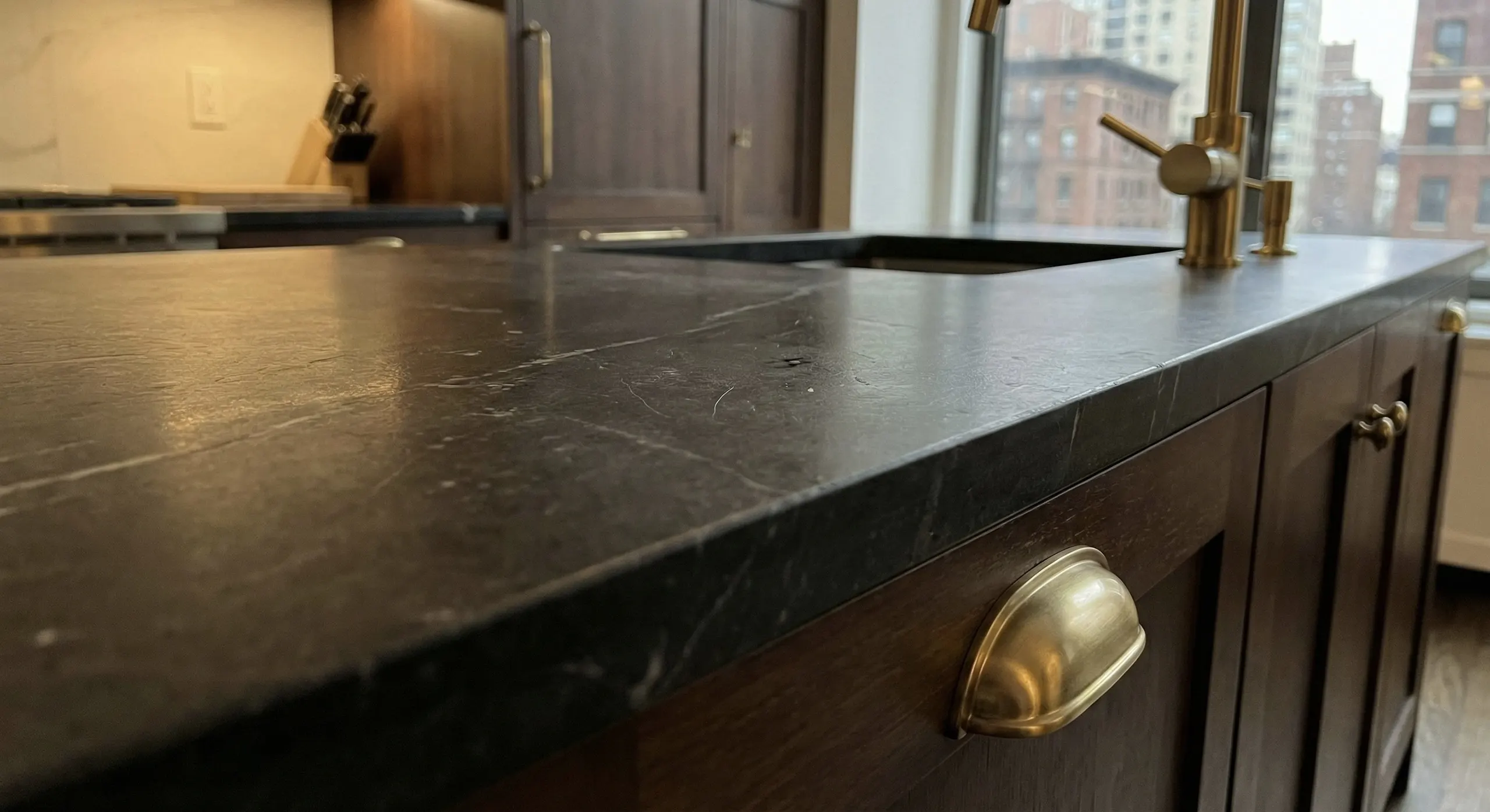 Matte Black Stone Kitchen Countertop with Brass Accents in Manhattan Apartment Matte black stone kitchen countertop with vintage brass hardware in a luxury Manhattan apartment renovation.