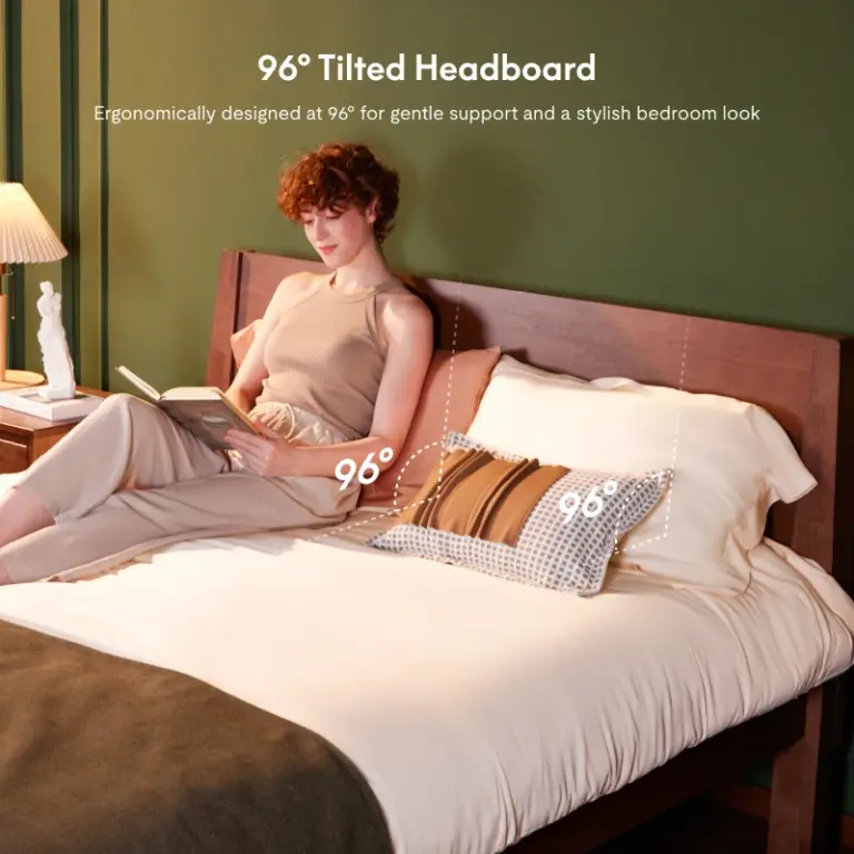 Person sitting up and reading against a solid wood headboard labeled &ldquo;96&deg; tilted headboard&rdquo; showing the supp