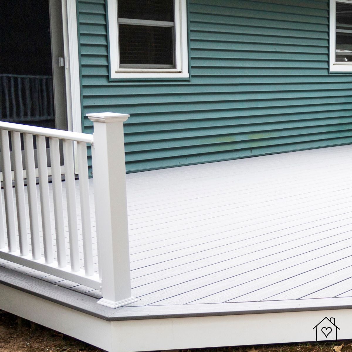 Gray deck with white railing against teal siding, showing clean picture-frame border and low-maintenance finish.