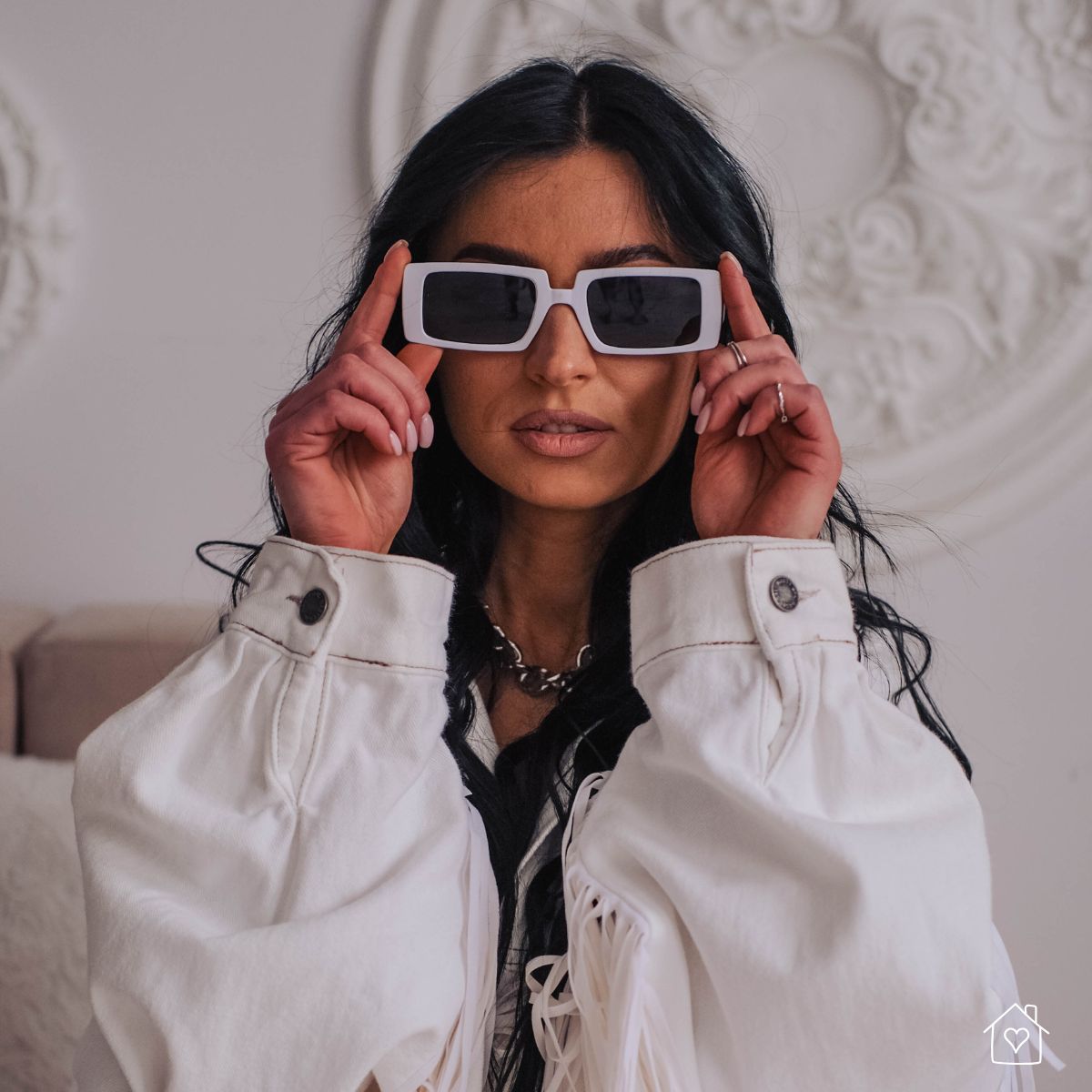 close-up portrait of woman indoors wearing rectangular white sunglasses and oversized jacket for a 90s-style home photoshoot