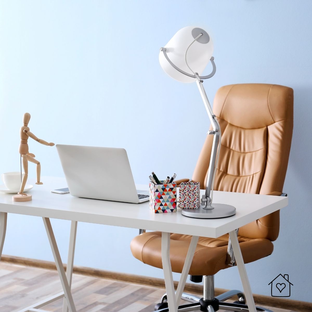 Tan leather high-back office chair beside a white minimalist desk with laptop and task lamp in a simple home office.