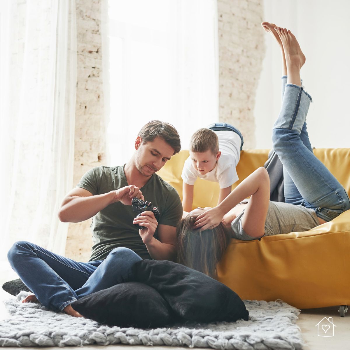 family relaxing on a sofa with natural window light during a casual home photoshoot