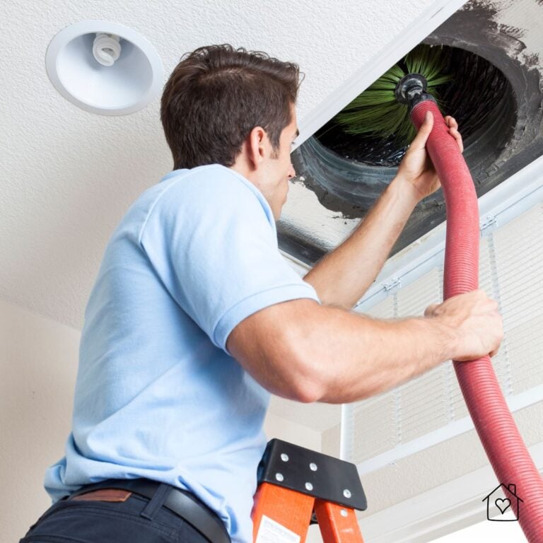 Professional air duct cleaning technician removing dust from a ceiling vent in a residential home.