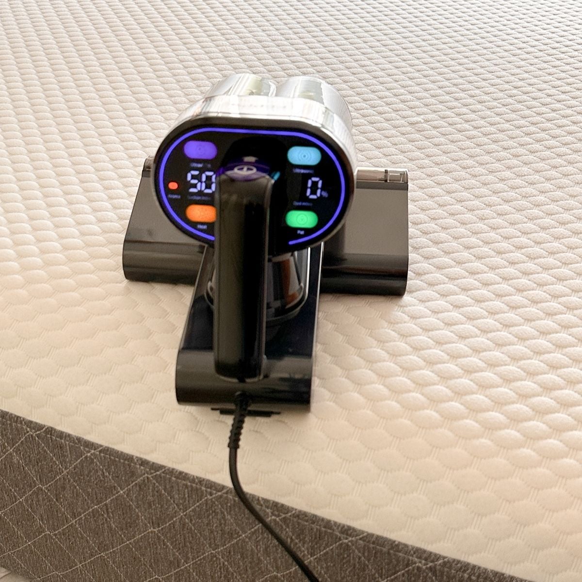 Close-up of the FEPPO mattress vacuum's illuminated control panel displaying dust mite percentage readings and cleaning mode buttons