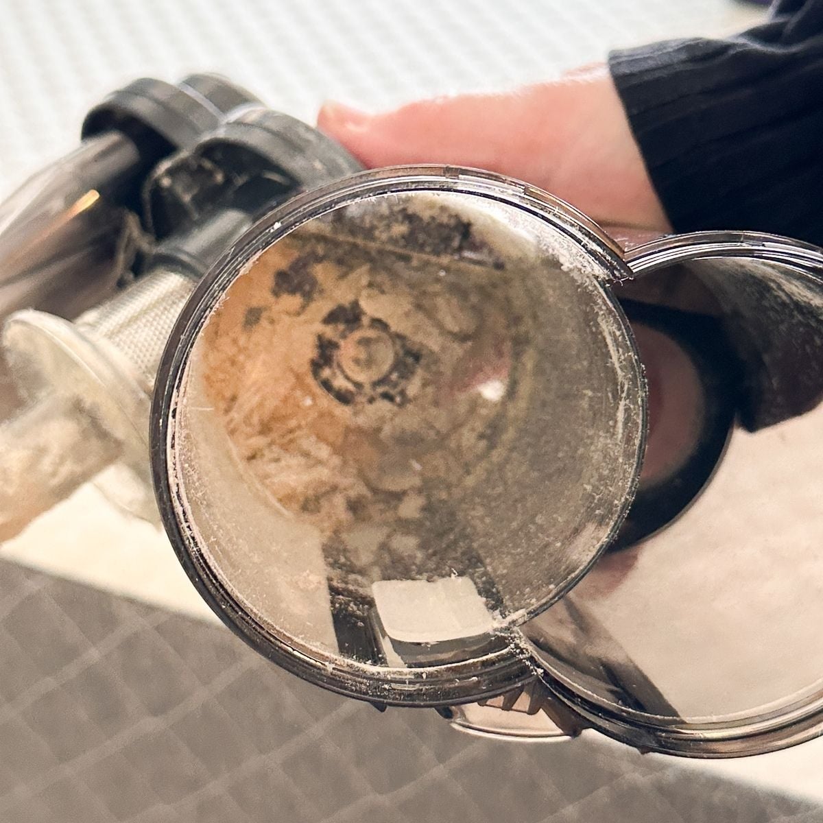 Interior view of the FEPPO mattress vacuum's dust bin revealing a significant buildup of fine dust particles after a single mattress cleaning session