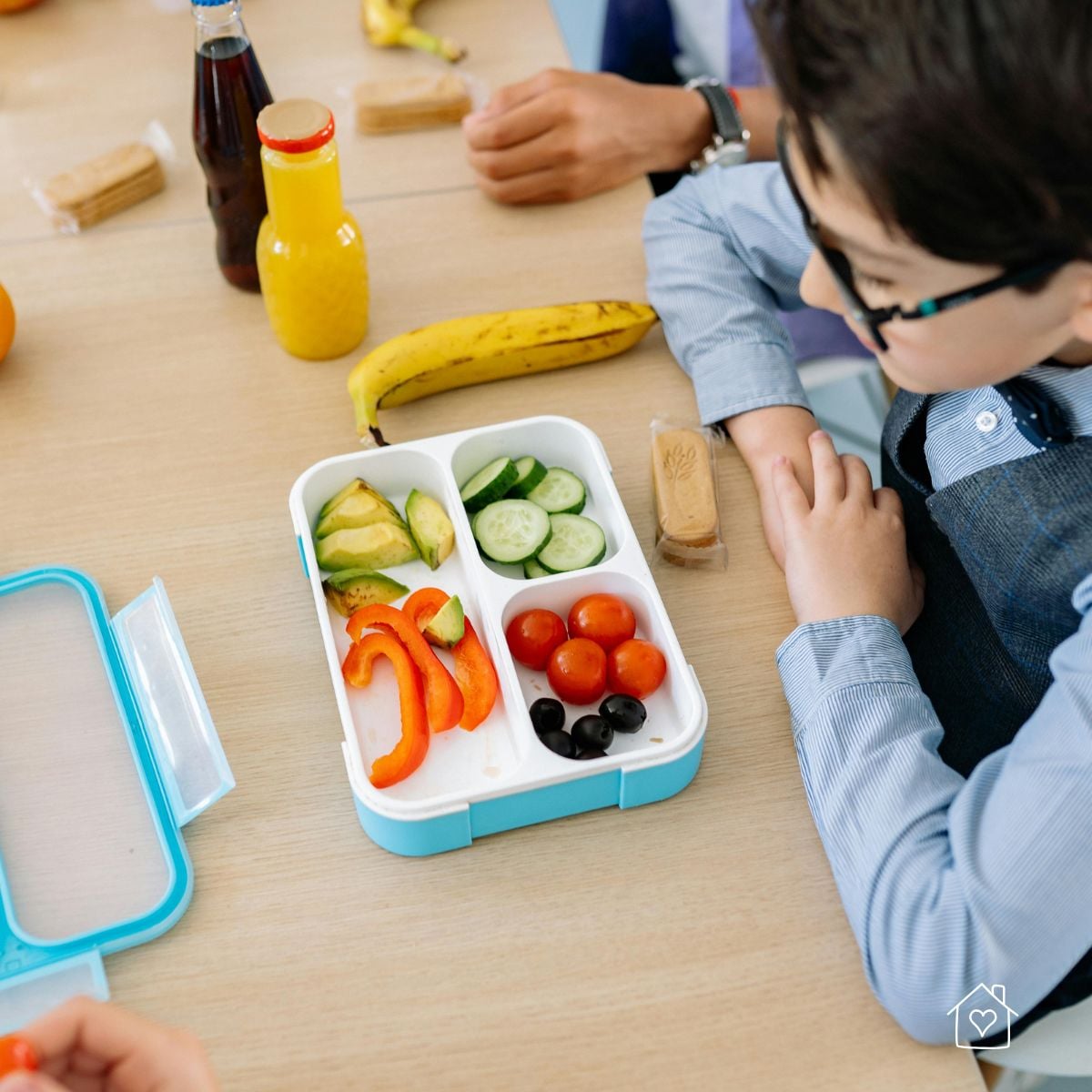 Purple lunchbox packed with sandwich slices, green grapes, waffle crackers, and carrot sticks for a school snack or lunch.