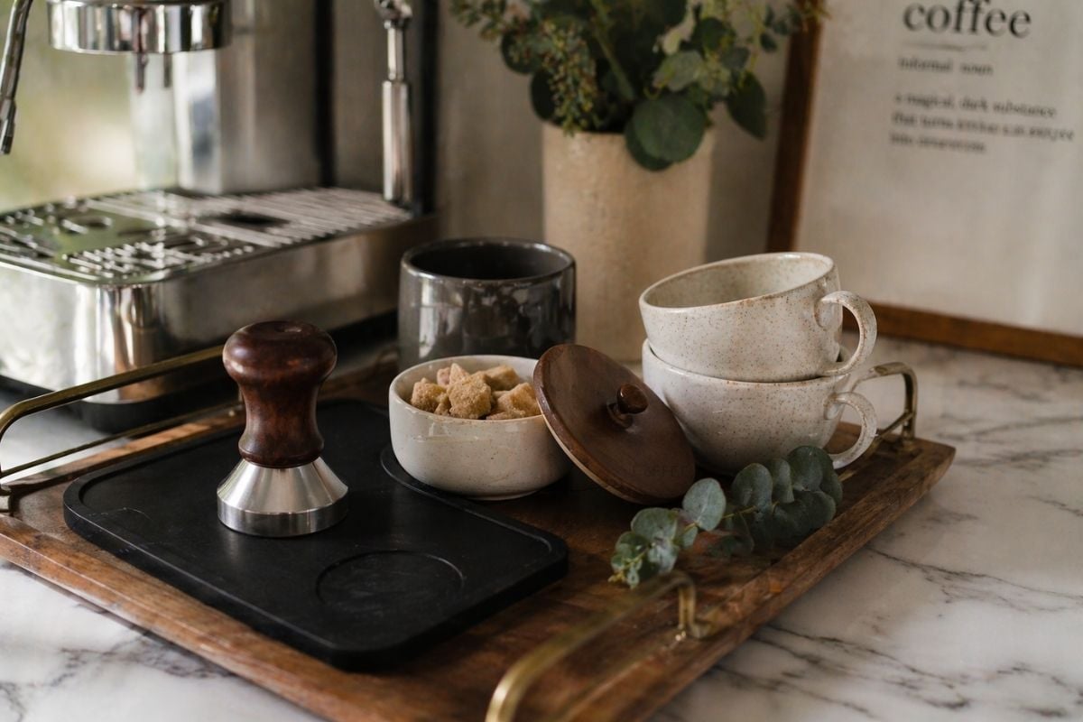 manual espresso machine set up as the centerpiece of a home coffee corner on a wood counter