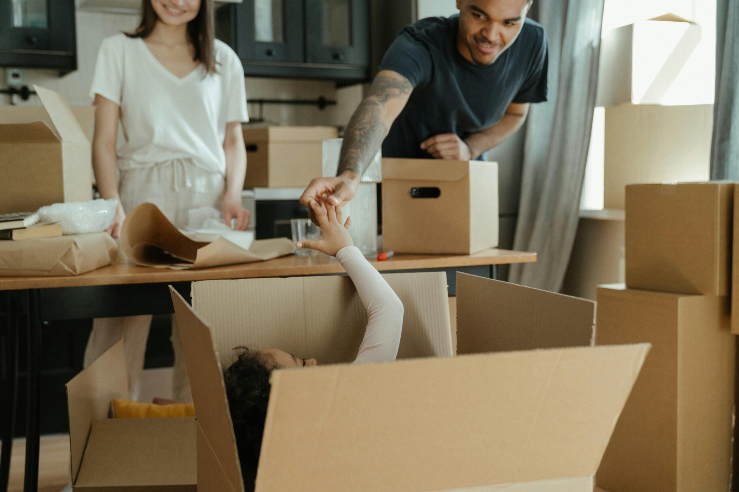 Family packing and organizing cardboard boxes together in a kitchen during a home move