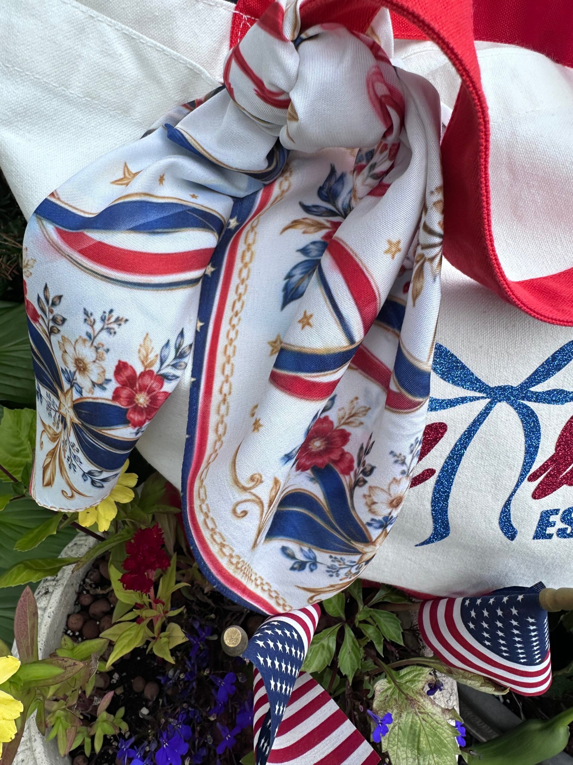 Close-up of patriotic red white blue and gold floral bandana scarf tied to canvas tote bag handle