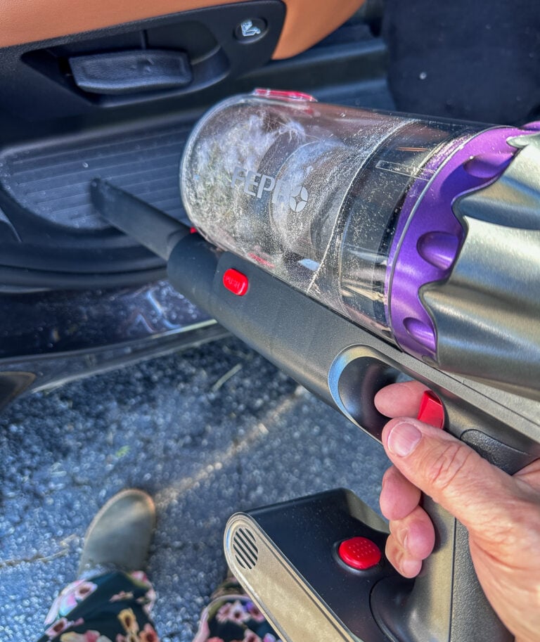 FEPPO cordless vacuum converted to handheld mode cleaning sand and debris from a car interior after a beach trip.