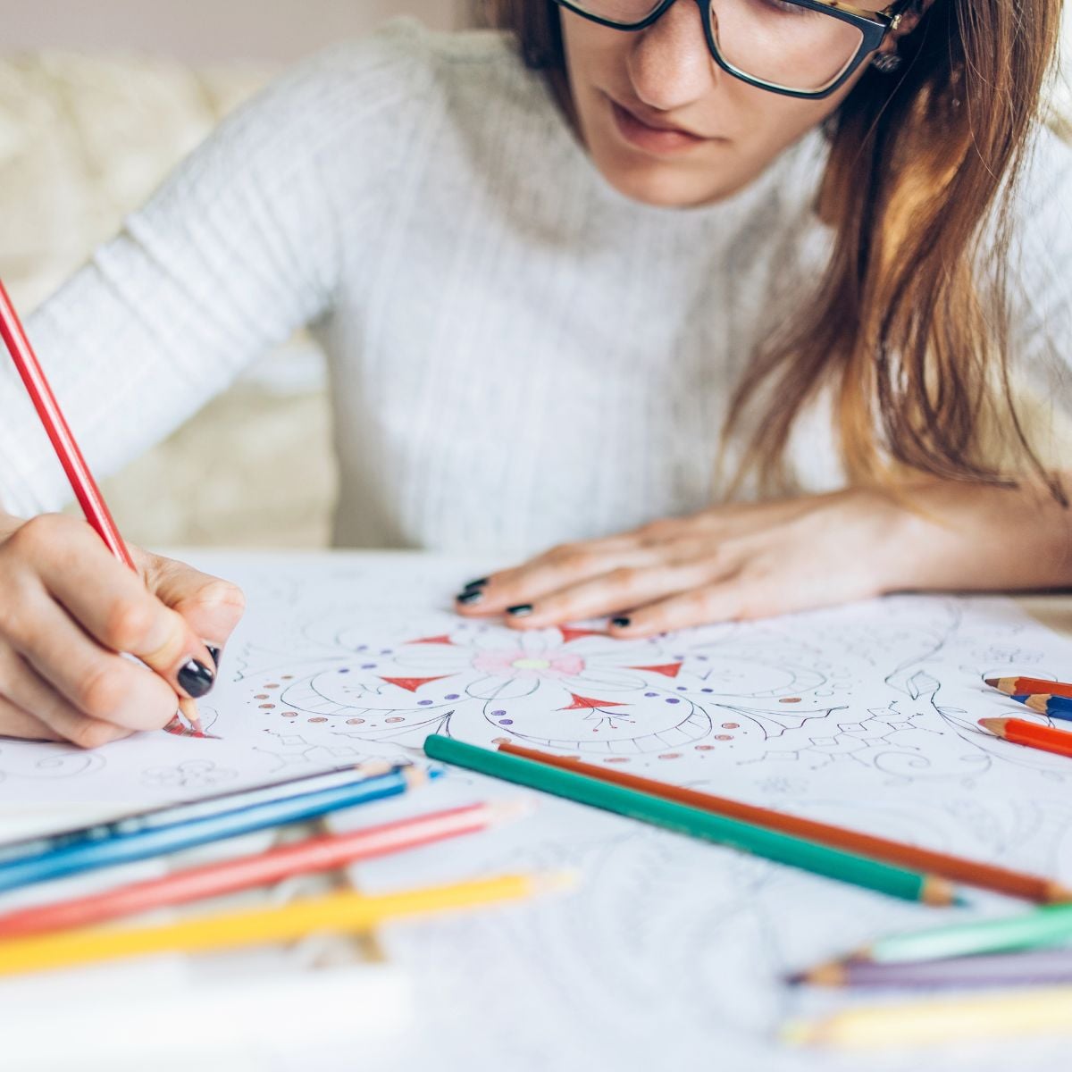 Woman coloring a detailed printable page with colored pencils as a relaxing screen-free activity