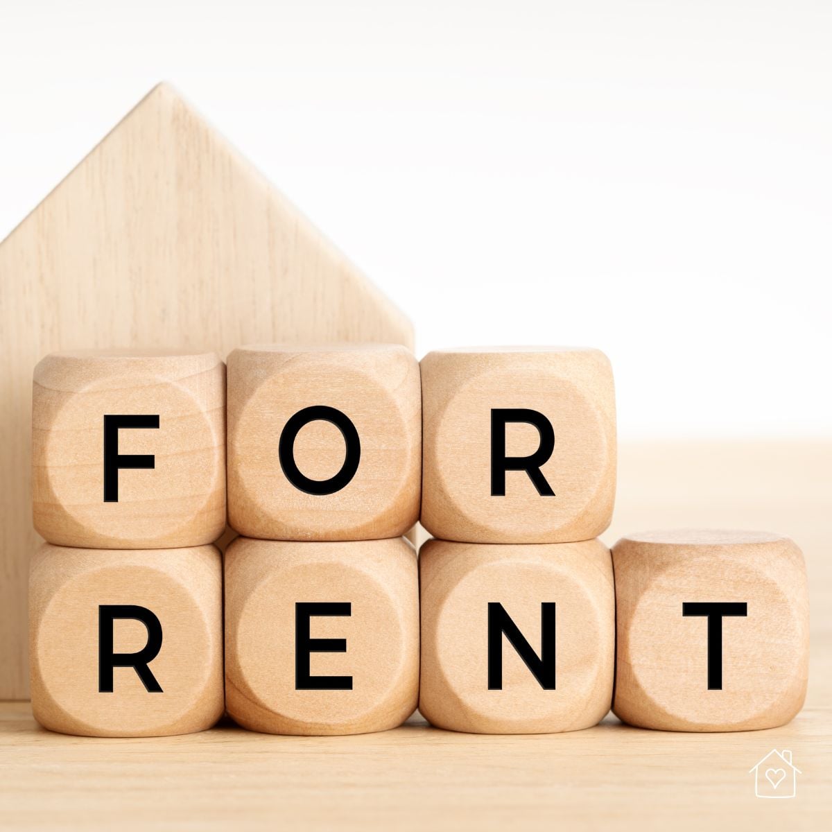 Wooden letter blocks spelling “For Rent” arranged in front of a wooden house shape.