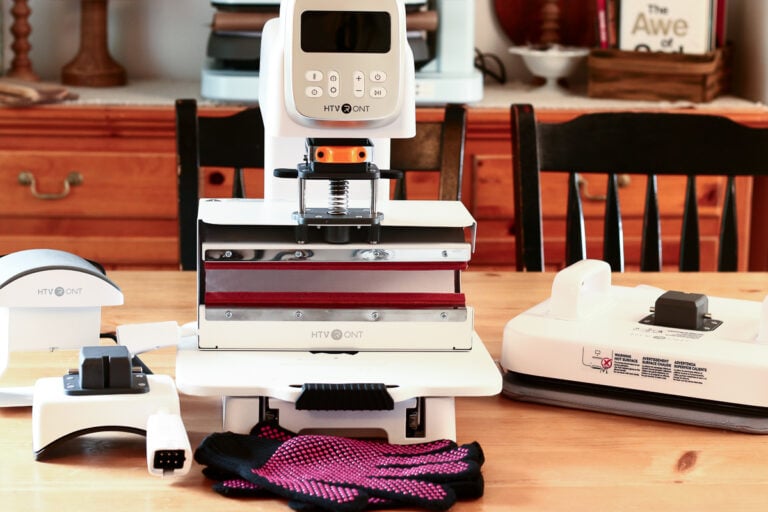 HTVRont A100 heat press with hat, tumbler and flat press modules laid out on a table