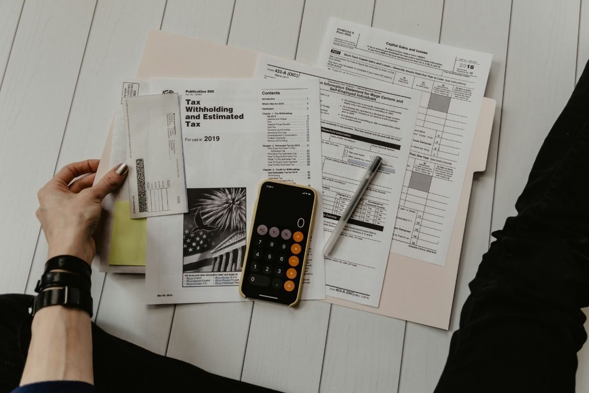 A person planning a monthly household budget with a calculator, pen and notepad.