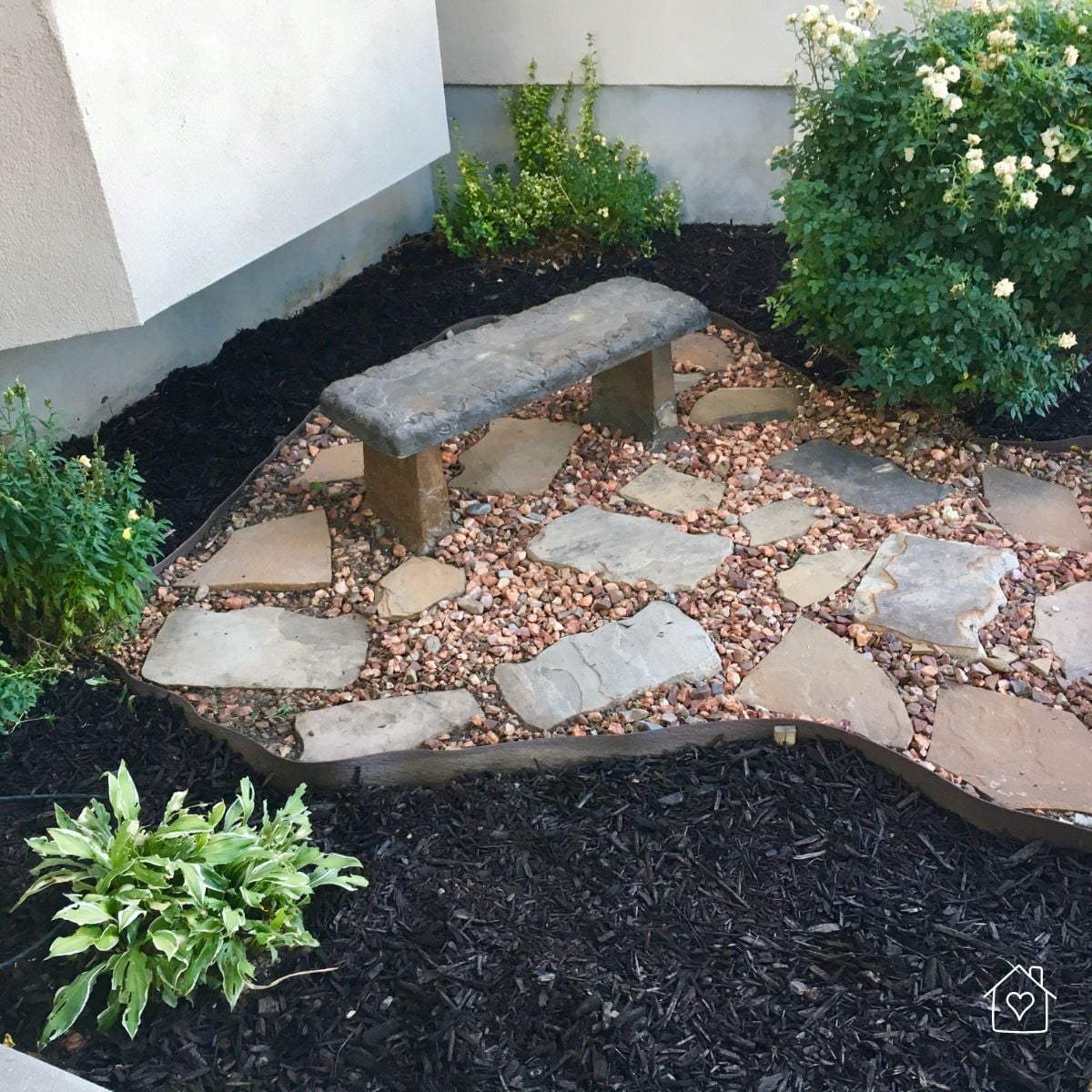 Well-maintained flower bed featuring fresh mulch, colorful blooming flowers, shrubs, and clean edging that helps prevent mulch erosion during heavy rainfall.