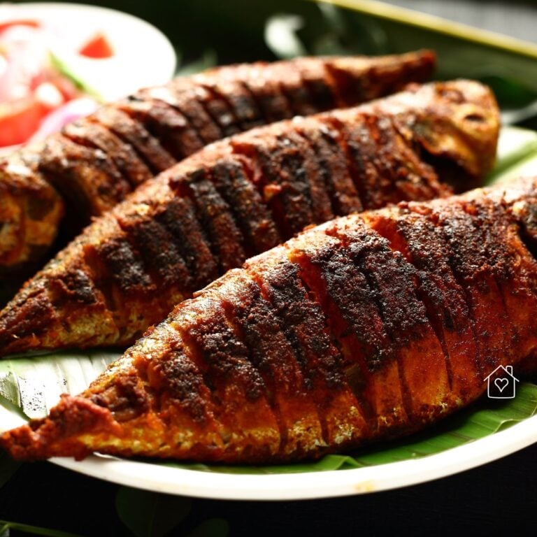 Whole spice-rubbed fish grilled and sliced, served on a banana leaf with tomato salad