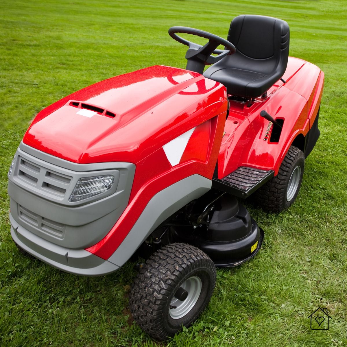 Red riding lawn mower parked on green grass, ready to operate on a large yard