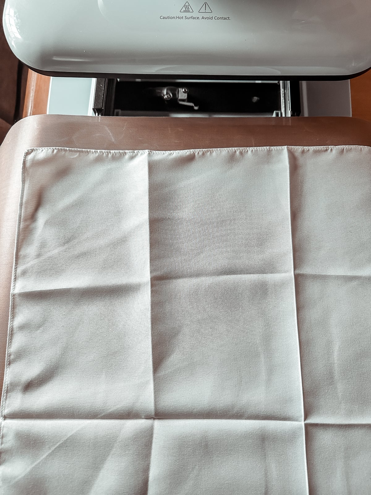 White polyester scarf blank laid flat on the heat press mat before pressing
