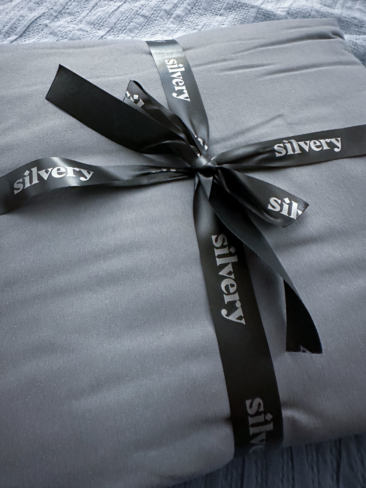 Folded gray Silvery Comfort Sheets tied with a black silvery satin ribbon