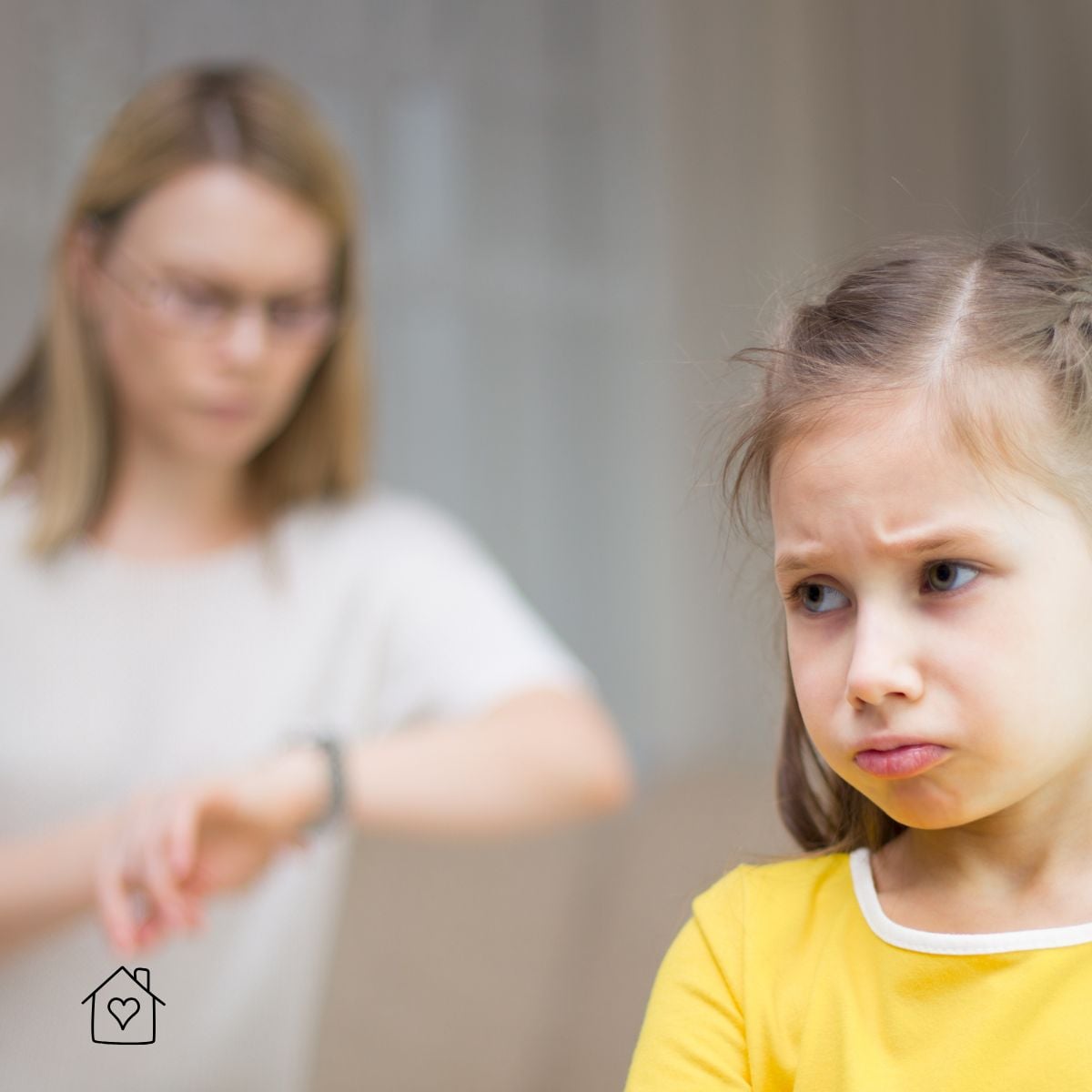 A mother checks her watch impatiently while her young daughter looks off with a hurt, frustrated expression