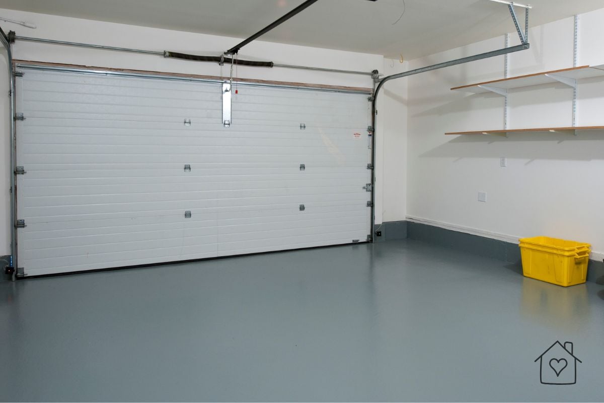 Interior view of a white paneled residential garage door with tracks and wall shelving