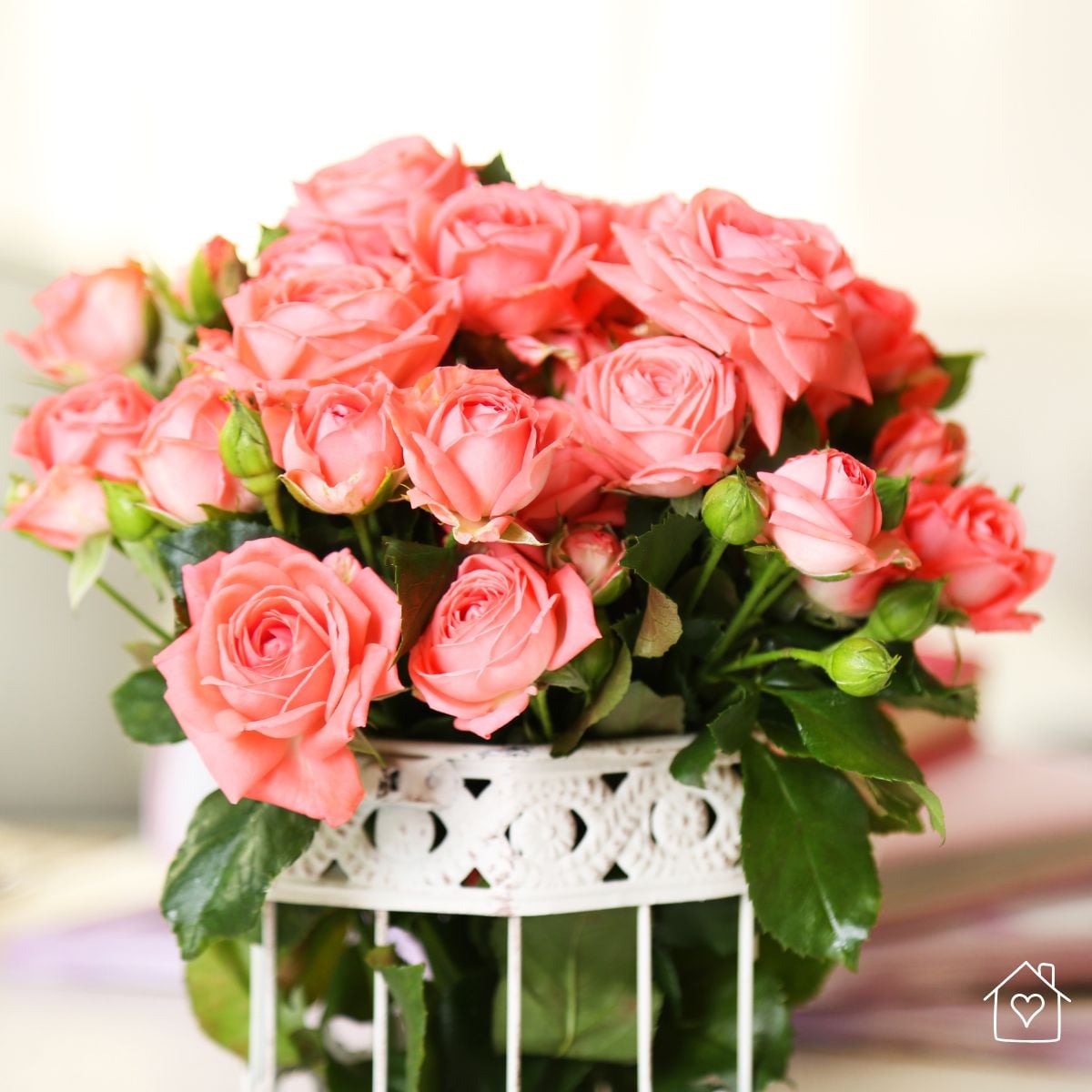 Coral rose arrangement in a vintage style white metal vase