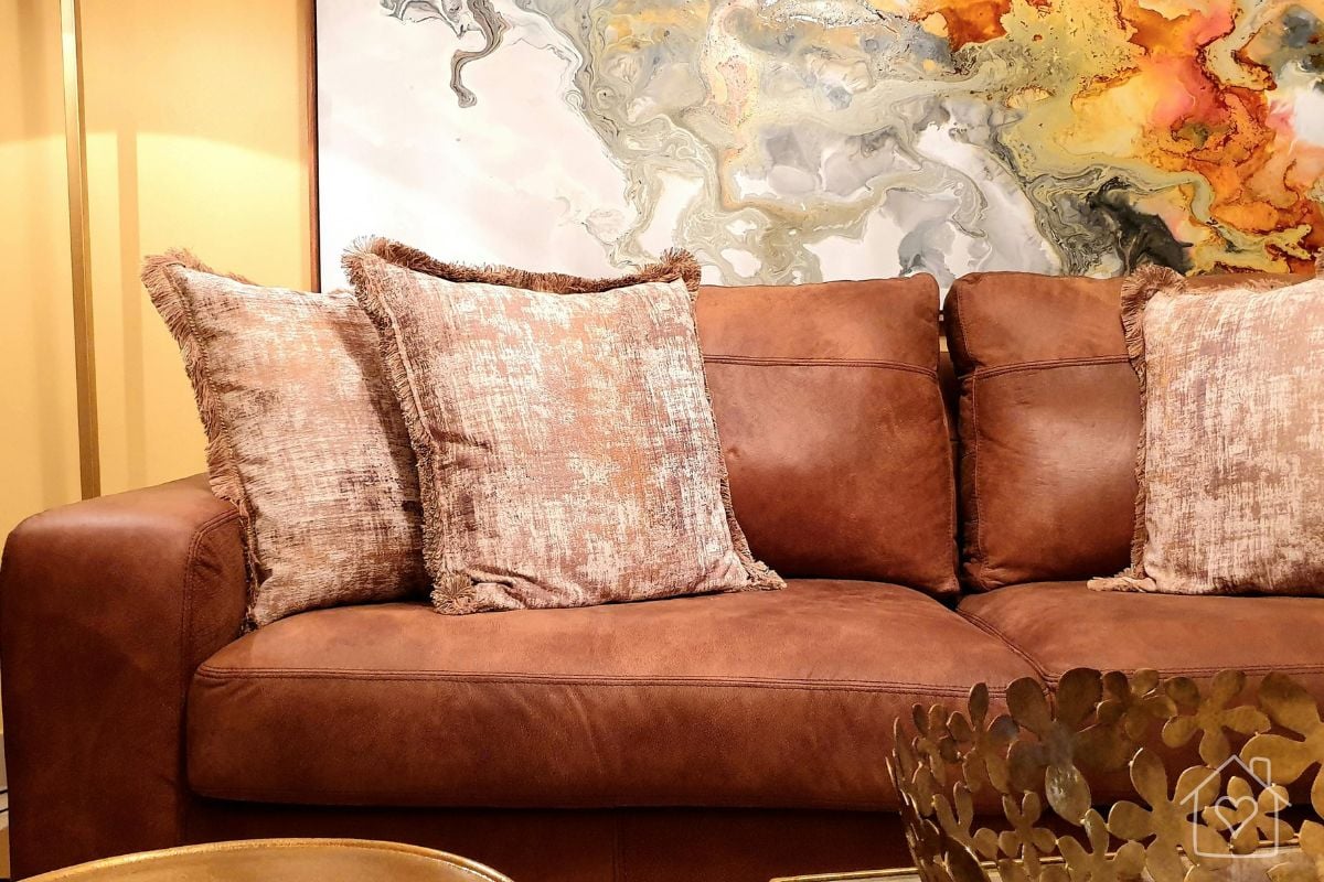 Cognac leather sofa with fringed pillows and a brass coffee table, styled as part of a living room refresh