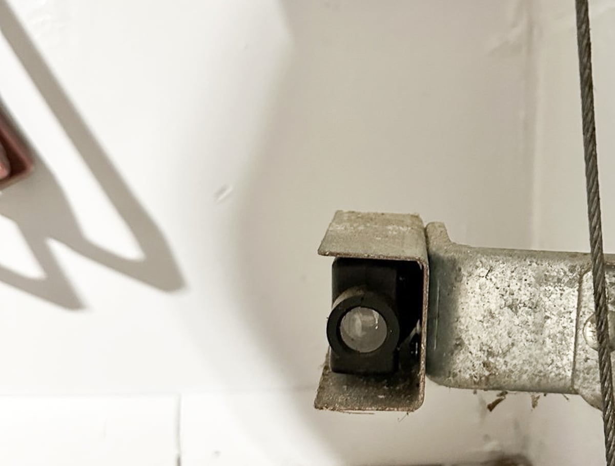 Garage door photo-eye safety sensor mounted near the bottom of the track