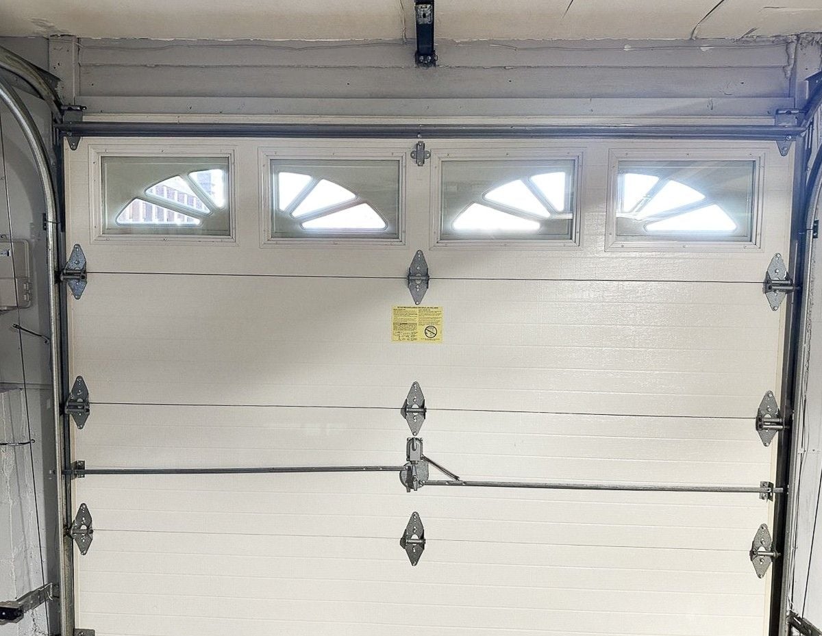 Inside view of straight, solid garage door panels with hinges and windows