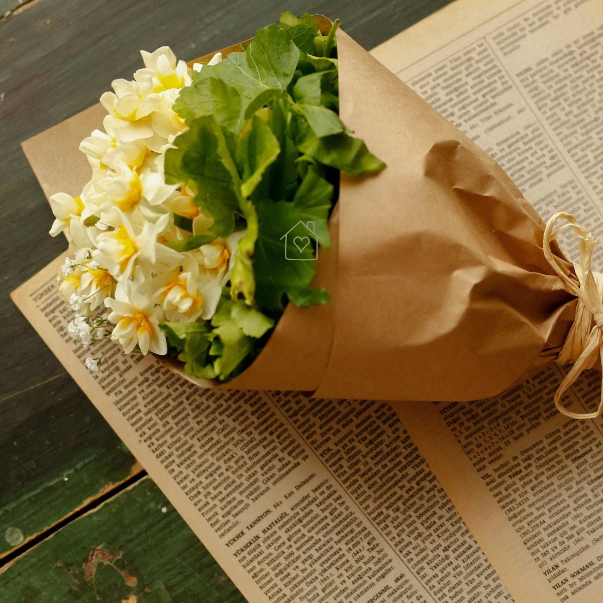 Small bouquet of cream and yellow daffodils and baby’s breath in kraft paper tied with raffia