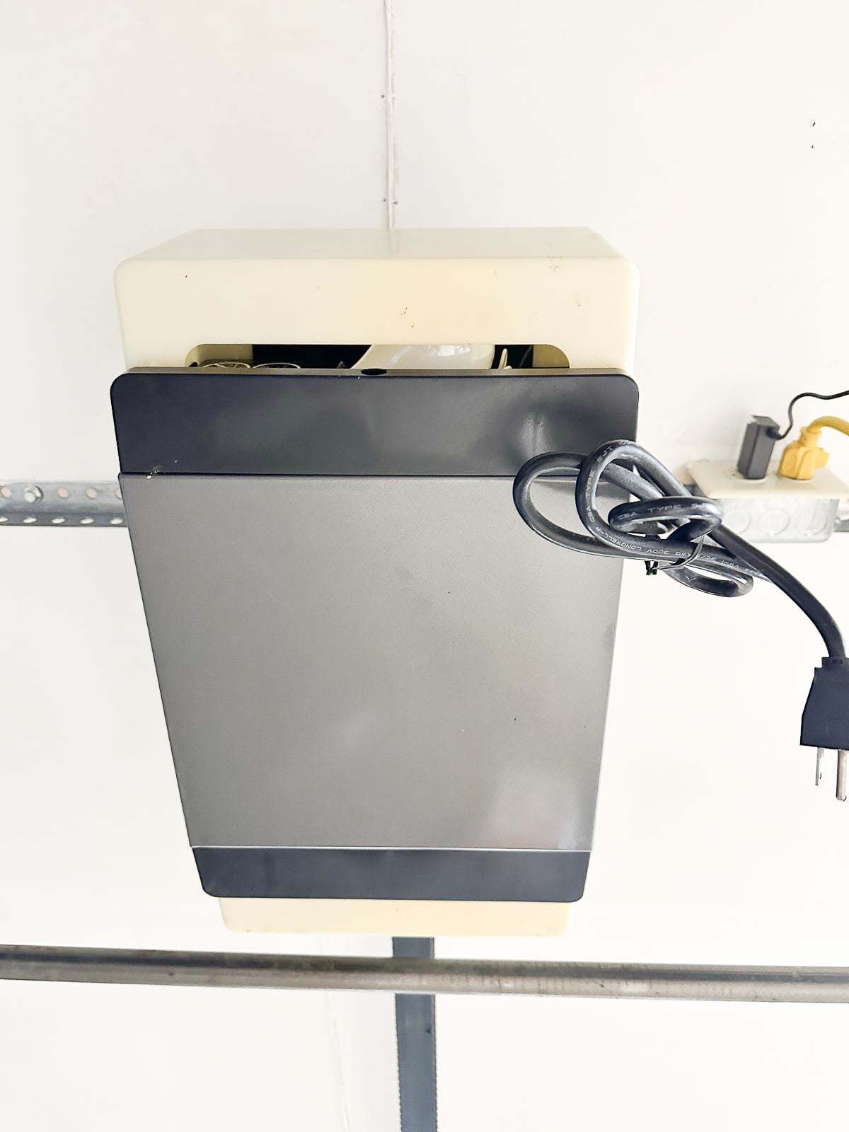 Older ceiling-mounted garage door opener with its power cord