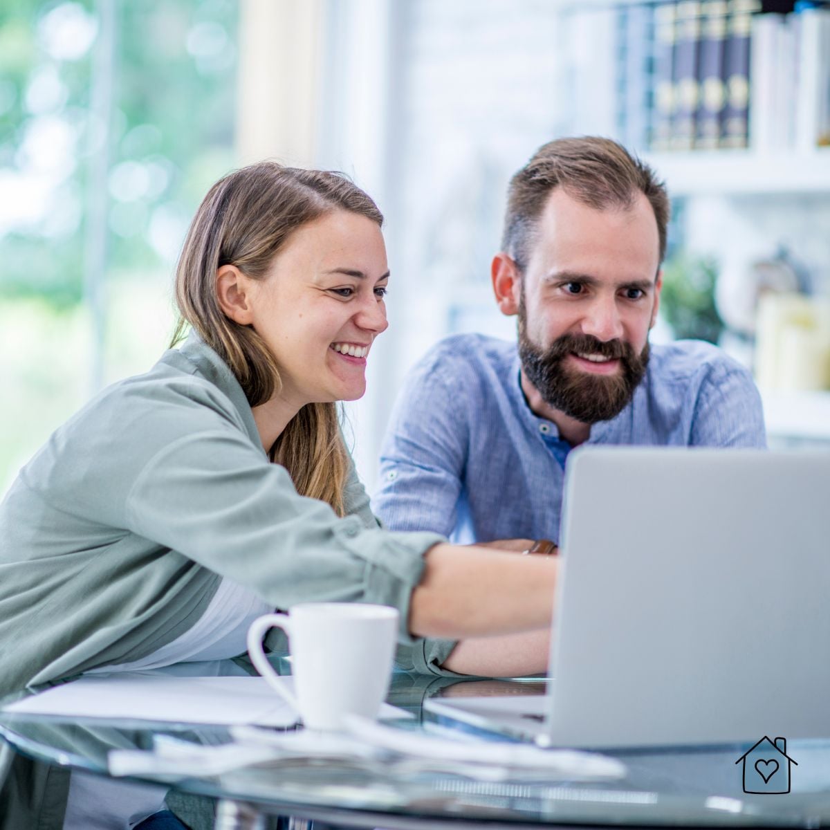 Smiling couple looking at a laptop together while planning a room makeover.