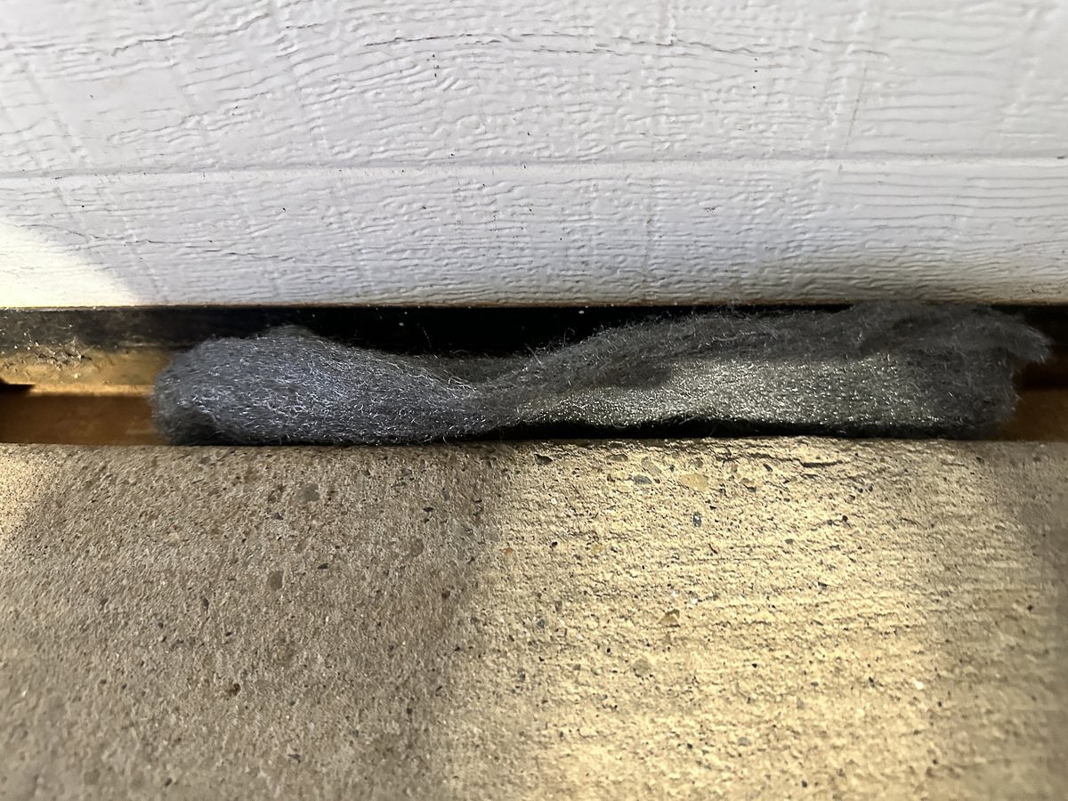 Steel wool packed into the gap between a garage door and the concrete floor